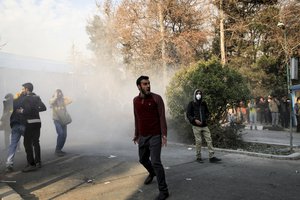 In this photo taken by an individual not employed by the Associated Press and obtained by the AP outside Iran, university students attend a protest inside Tehran University while a smoke grenade is thrown by anti-riot Iranian police, in Tehran, Iran, Saturday, Dec. 30, 2017.