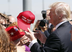 President Donald Trump hands a signed "Make America Great Again," hat back to a supporter, Wednesday, Aug. 23, 2017, in Reno, Nev.