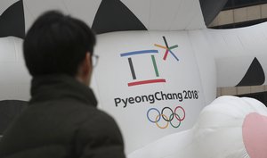 A man walks by an official emblem of the 2018 Pyeongchang Olympic Winter Games, in downtown Seoul, South Korea, Friday, Dec. 29, 2017.