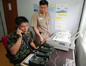 South Korean Lt. Choi Don-rim, left, communicates with a North Korean officer during a phone call at a military office near the demilitarized zone separating the two Koreas in Paju, about 55 kilometers (31 miles) north of Seoul, Wednesday, Aug. 10, 2005.