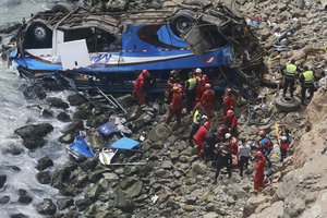 In this photo provided by the government news agency Andina, firemen recover bodies from a bus that fell off a cliff after it was hit by a tractor-trailer rig, in Pasamayo, Peru, Tuesday, Jan 2, 2018.