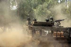 Israeli soldiers ride near the border with Gaza, Saturday, July 19, 2014. Israel pounded Hamas rocket launchers, uncovered more than a dozen cross-border tunnels and engaged in gunbattles with Palestinian militants Saturday, as fighting intensified on the second day of its open-ended ground operation in Gaza, as the Palestinian death toll continued to rise.