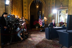 File - President Donald J. Trump talks with members of the military via video tele conference Sunday, December 24, 2017, from the library of Mar-a-Lago in West Palm Beach, Florida.