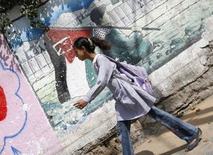 A Palestinian boy poses in front of a mural painting on the theme of return of refugees to their land in what is now Israel, in Gaza City on June 12, 2012. Photo by Ahmed Deeb/ WN.