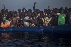 FILE- In this Saturday Sept. 10, 2016 file photo, African refugees and migrants react aboard a partially punctured rubber boat as they wait to be assisted , during a rescue operation on the Mediterranean Sea, about 13 miles North of Sabratha, Libya.