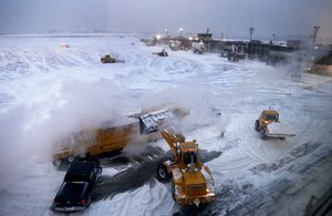 Front Loaders dump snow into a snow melter while clearing the apron around Gates C and D at Terminal B at LaGuardia Airport, Thursday, Jan. 4, 2018, in New York.