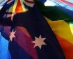 a silhouetted figure holding two flags - the australian flag and the rainbow flag