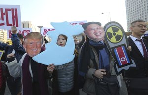 Anti-war protesters wearing a mask of the U.S. President Donald Trump and North Korean leader Kim Jong Un, right, march after a rally demanding peace of the Korean peninsula near the U.S. Embassy in Seoul, South Korea, Sunday, Nov. 5, 2017.