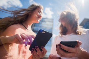 The end of roaming charges in the EU in June 2017: Two young women using their smartphones