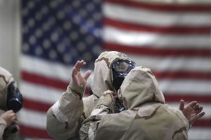 Air Force Tech. Sgt. Christina Smith, right, and Senior Airman Frank O’Dell work together to properly put on their mission oriented protective posture gear during chemical, biological, radiological, and nuclear defense training held at the North Carolina Air National Guard Base, Charlotte Douglas International Airport, N.C., Jan. 8, 2018.