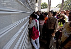 In this Jan. 6, 2018 photo, shoppers take a peek as they line up outside a supermarket to buy food at discounted prices, in Caracas, Venezuela.