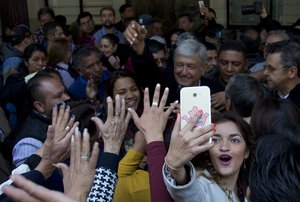 File - A woman takes a selfie backdropped with presidential hopeful Andres Manuel Lopez Obrador during a pre-campaign rally in Mexico City, Friday, Dec. 15, 2017.