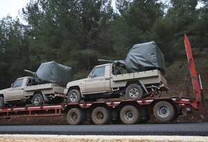 A truck, part of a convoy, carrying military pickup trucks with machine guns attached is seen on the outskirts of the village of Sugedigi, Turkey, Sunday, Jan. 21, 2018.