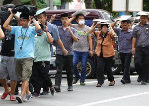 Hotel employees cover their heads as they evacuate to safety at the start of the four-day quake drill around the country Friday, July 14, 2017 in Manila, Philippines.