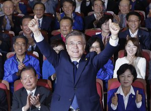 South Korea's presidential candidate Moon Jae-in of the Democratic Party raises his hands as his party leaders and members  watch on television local media's results of exit polls for the presidential election in Seoul, South Korea