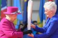 Queen Elizabeth II, left, holds the relay baton with Louise Martin, the President of the Commonwealth Games Federation, ...