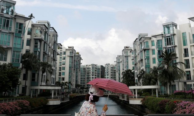 A woman passes a private condominium estate in Singapore February 13, 2017. Photo: Reuters/Edgar Su