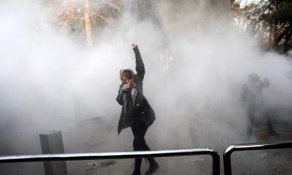 An Iranian woman raises her fist through the smoke of tear gas at the University of Tehran. Photo: AFP