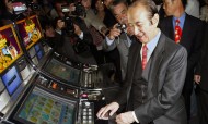 Macau's gambling tycoon Stanley Ho (center) is surrounded by photographers as he operates a slot machine during the opening of a new casino in Lisbon, Portugal, on April 19, 2006. Photo: AFP / Francisco Leong