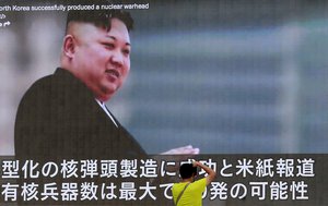 A man takes a photo of a TV news program showing an image of North Korean leader Kim Jong Un while reporting North Korea's rocket launch in Tokyo, Wednesday, Aug. 9, 2017.