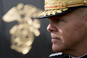 The Marine Corps insignia is visible behind Commandant of the Marine Corps Gen. Robert B. Neller as he takes questions from reporters at the unveiling of the Iraq and Afghanistan campaign engravings on the USMC War Memorial (Iwo Jima), Tuesday, Nov. 21, 2017, in Arlington, Va.