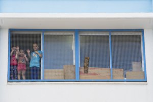 File - Children look out from a window during Secretary-General Ban Ki-moon’s visit with internally displaced persons (IDPs) at the UN Relief and Works Agency for Palestine Refugees in the Near East (UNRWA) Collective Centre in Gaza, 14 October, 2014.