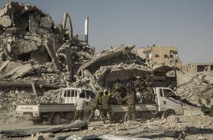 Members of the U.S.-backed Syrian Democratic Forces (SDF) ride near near the main traffic circle in Raqqa Syria, Friday, Oct. 20, 2017.