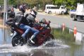 Motorbike riders travel through saltwater flooding in Scarborough, north of Brisbane.