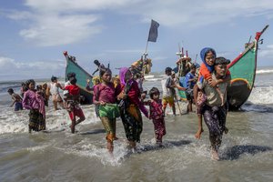 Rohingya Muslims walk to the shore after arriving on a boat from Myanmar to Bangladesh in Shah Porir Dwip, Bangladesh, Thursday, Sept. 14, 2017.