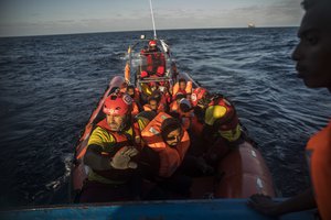 In this Saturday Jan. 27, 2018 photo, aid workers of the Spanish NGO Proactiva Open Arms transfer a group of refugees and migrants from an overcrowded wooden boat to a Spanish war-ship, 45 miles north of Al-Khums, Libya.