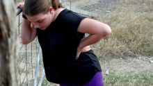 A teenager rests at a gate after a run.