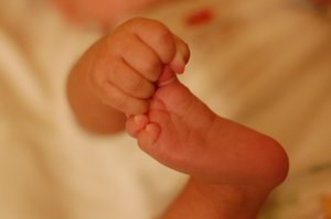 A newborn baby (toddler) holding his feet