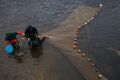 John Taylor, right, and Suzanne Smith collect elvers from nets left out overnight in Pemaquid, Maine.