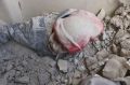 This photo provided by the Syrian Civil Defense group known as the White Helmets, shows a child partly buried in rubble ...