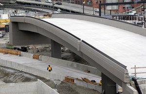 In this photo taken Tuesday, Sept. 19, 2017, a worker walks under a portion of a new offramp for Highway 99 where a tunnel for the roadway is still being constructed in Seattle. The offramp has a new type of column that flexes when the ground shakes in an earthquake, then snaps back to its original position so that the structure not only survives a quake without collapsing but also sustains so little damage that it can be used immediately.