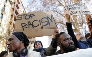 A man holds a sign reading "Stop Racism" during an anti-racism demonstration following last Saturday’s attacks in the Italian city of Macerata when six Africans were wounded in a two-hour drive-by shooting spree by a right-wing extremist, in Milan, Italy, Saturday, Feb. 10, 2018.