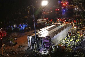 Firemen hurry to try to remove injured passengers from a double-decker lying on its side in Hong Kong, Saturday, Feb. 10, 2018.