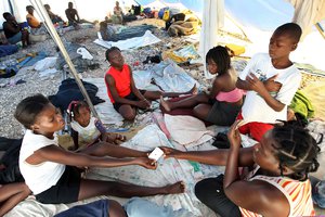 File - Displaced Haitians following the earthquake who have not yet been assigned individual tents share a large tent house at a new camp site in Croix-des-Bouquets, Haiti, April, 2010.