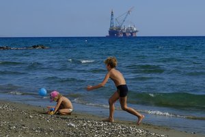 In this photo taken on Sunday, Oct. 15, 2017 children play on a beach with a drilling platform seen in the background, on the outskirts of Larnaca port, in the eastern Mediterranean island of Cyprus. Turkish warships on maneuvers in the Mediterranean Sea have blocked a rig belonging to the Italian energy firm ENI from reaching an area off Cyprus to start searching for gas, officials said Saturday, Feb. 10, 2018.