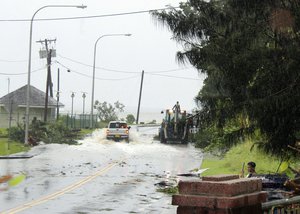 In this Friday, Feb. 9, 2018 photo, first responders with a backhoe work amid strong winds and heavy rain from Tropical Storm Gita to clear part of the main road at Fagaalu village in American Samoa.