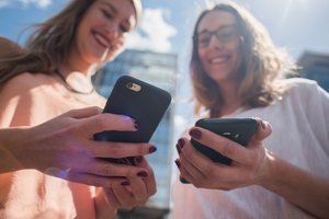 The end of roaming charges in the EU in June 2017: Two young women using their smartphones