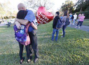 A family member who wished not to be identified, hugs a young girl, Wednesday, Feb. 14, 2018, in Parkland, Fla.