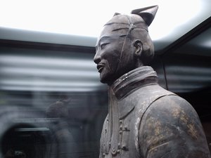 A stone warrior stands in a glass display case in the Terracotta Warriors museum, Xi'an