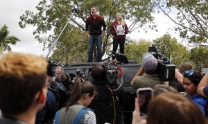 Organizers Cameron Kasky, left, and Jackie Corin, student survivors from Marjory Stoneman Douglas High School address fellow students before boarding buses in Parkland, Fla., Tuesday, Feb. 20, 2018, to rally outside the state capitol.