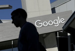 FILE - In this Nov. 12, 2015, file photo, a man walks past a building on the Google campus in Mountain View, Calif.