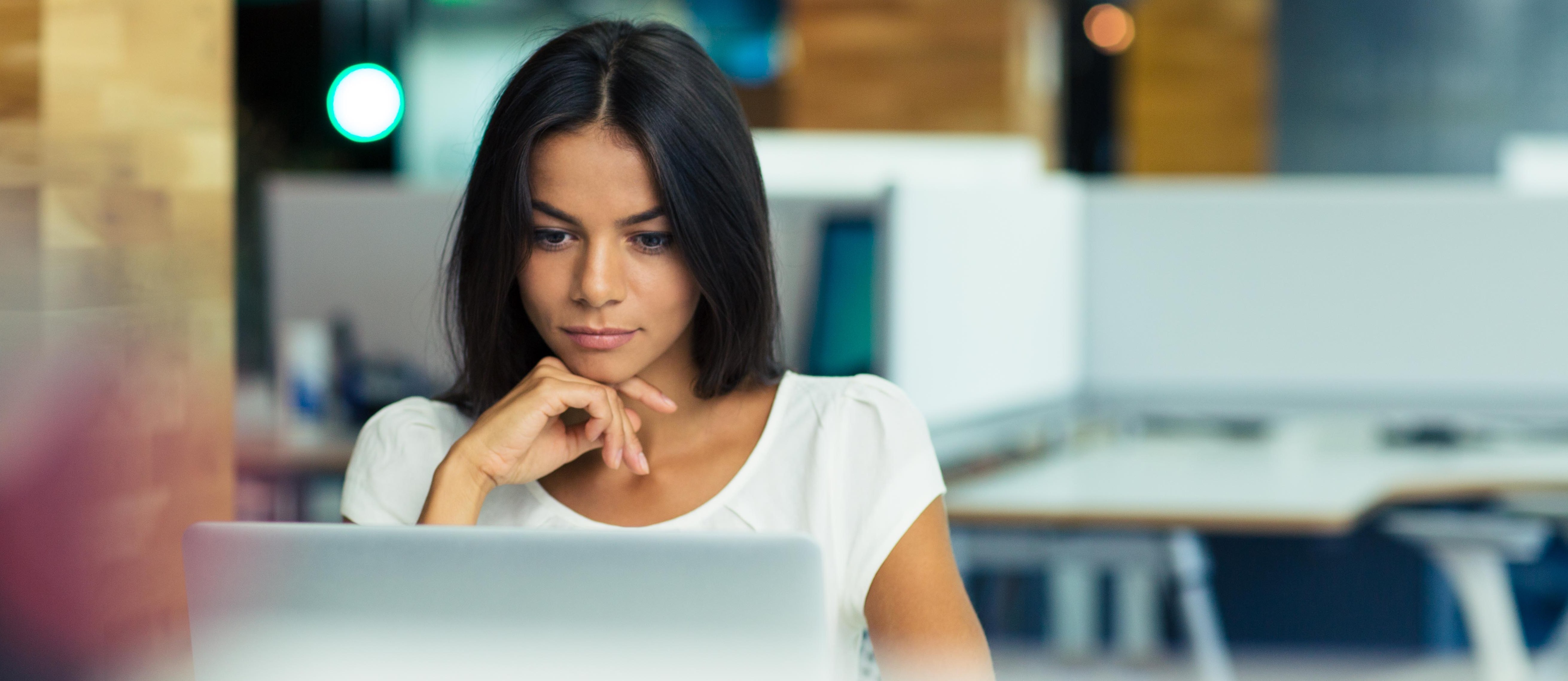 Young woman looking at a laptop, looking pensive.