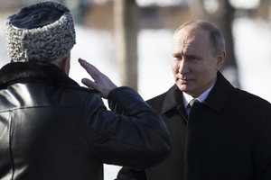 Russian President Vladimir Putin, right, listens to Defense Minister Sergei Shoigu's report as he arrives to attend a wreath-laying ceremony at the Tomb of the Unknown Soldier in Moscow, Russia, Friday, Feb. 23, 2018.