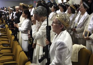 A woman wears a crown and holds an unloaded weapon during services at the World Peace and Unification Sanctuary, Wednesday Feb. 28, 2018 in Newfoundland, Pa. Worshippers clutching AR-15 rifles participated in a commitment ceremony at the Pennsylvania-based church.