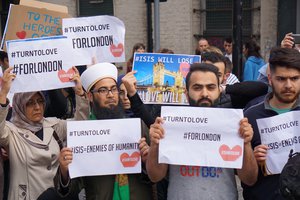 Muslims hold signs saying "ISIS WILL LOSE" and "#TURNTOLOVE" on Sunday June 4, 2017 at the police cordon surrounding the site in south London of the deadly van-and-knife attack that killed several people on Saturday night.