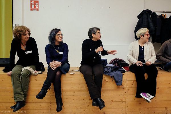 Four women seated on a low wall at a WordPress meetup.